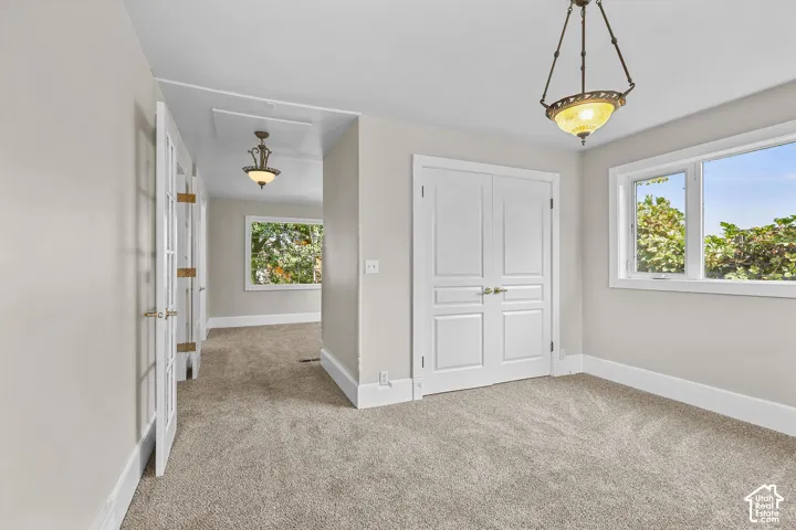 Plush carpet flooring, dual pane windows, elegant ceiling light fixture, and white paneled doors