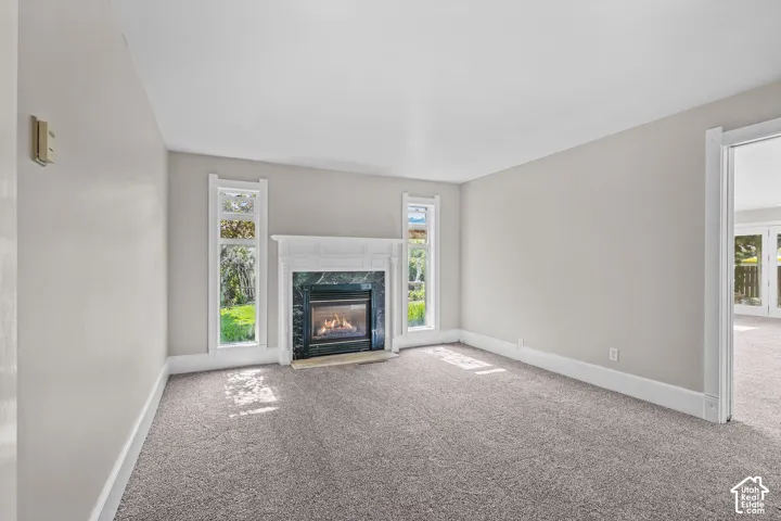 Fireplace with a decorative white mantel, dark stone surround, and light carpet flooring