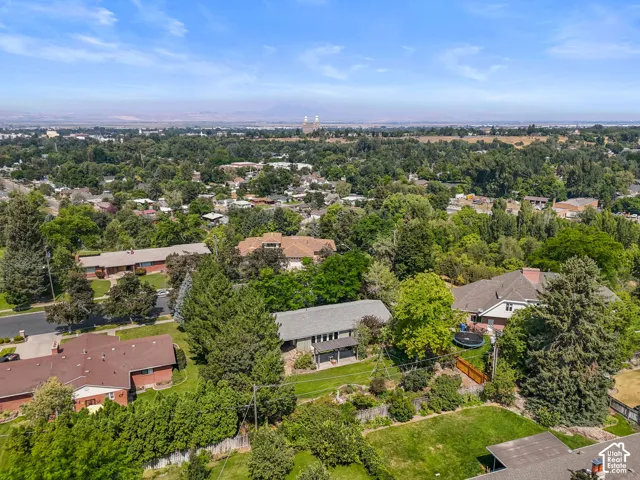 Aerial perspective showcasing mature landscaping with established trees throughout the property, expansive manicured lawn, and a residential setting within an established neighborhood