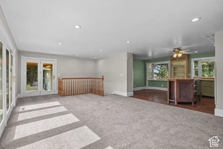 Recessed lighting, wood-finish flooring, light grey carpeting, painted wood balusters, and transom windows