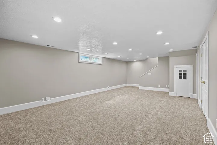 Expansive room featuring recessed lighting, plush carpeting, light gray walls, and white trim