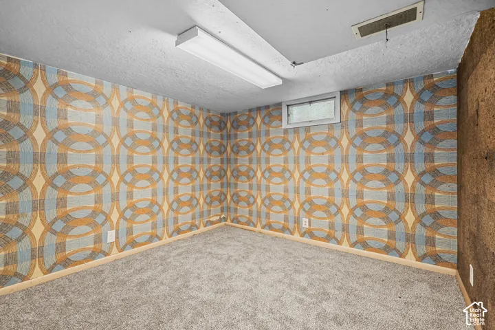 Textured wallcovering with a geometric pattern, neutral carpet flooring, and a flush-mount ceiling light fixture