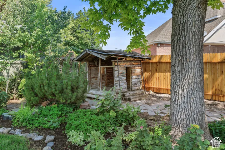 Landscaped yard with a wooden shed, mature trees, and a privacy fence