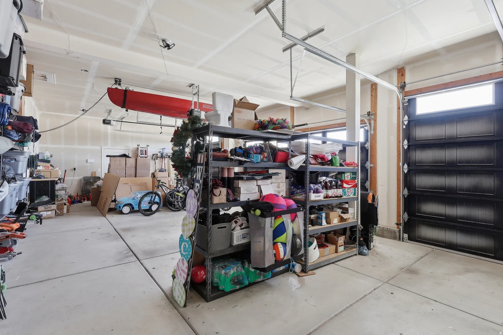 Attached garage space featuring a concrete floor, overhead storage system, and built-in shelving