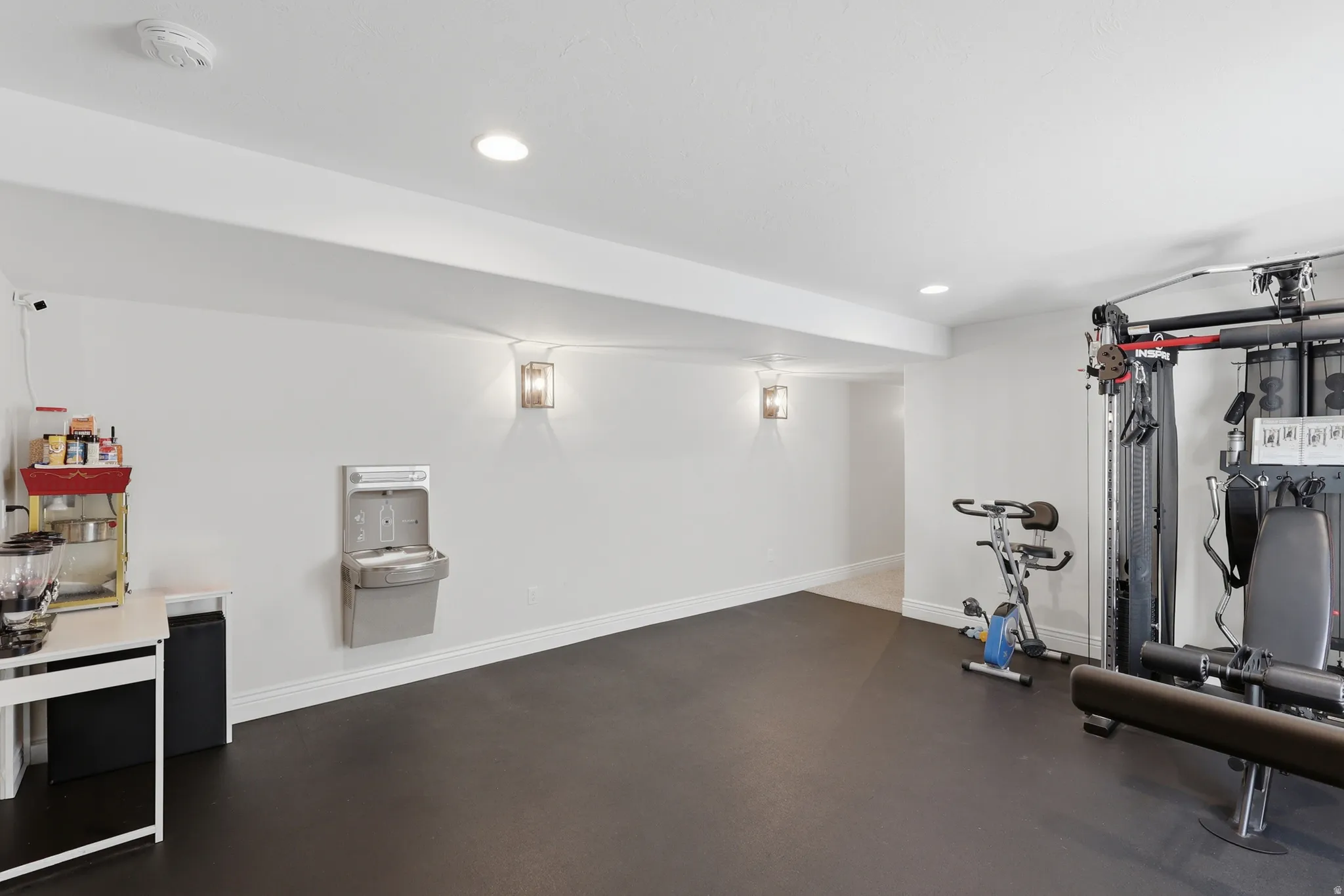 Expansive room featuring durable flooring, recessed lighting, and wall-mounted sconces