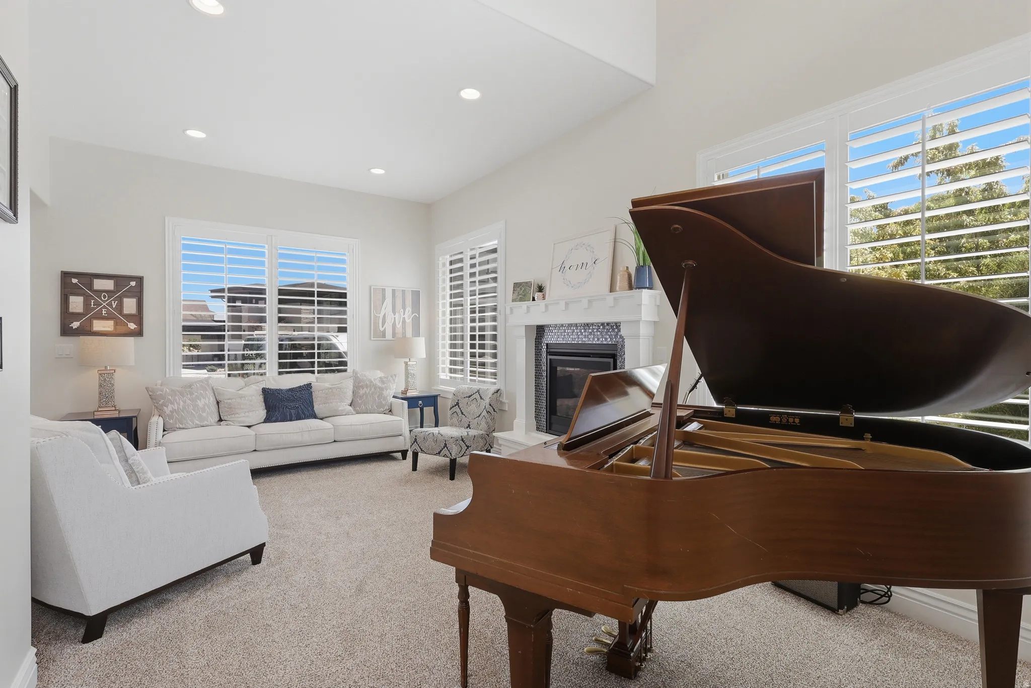 Living area featuring high vaulted ceilings, recessed lighting, multiple windows with shutters, and a fireplace with a decorative mantel and hearth