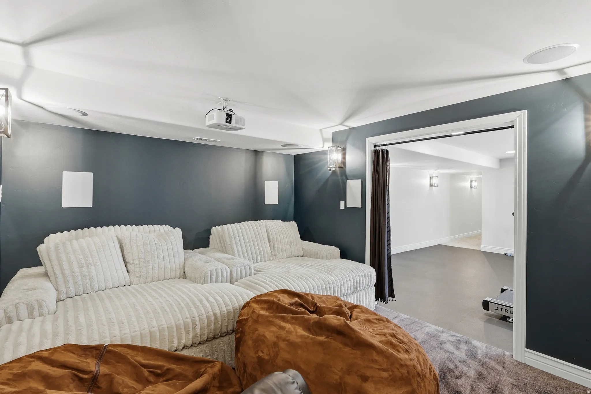 Integrated ceiling speakers, wall-mounted sconce lighting, recessed projector, and a wide cased opening