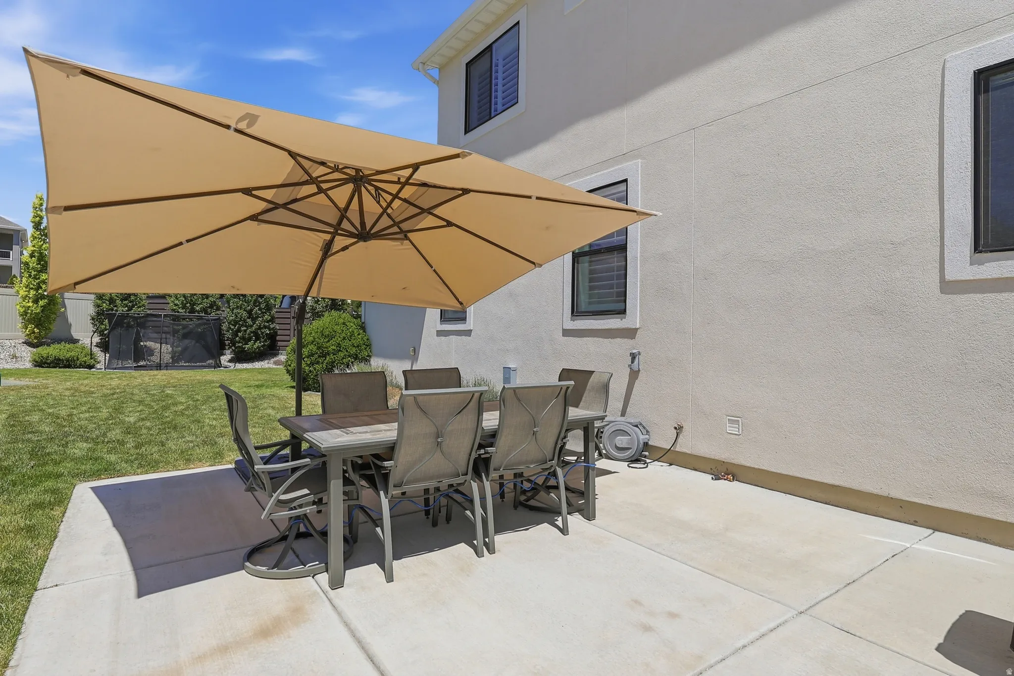 Concrete patio with stucco exterior, rear yard access, and upper-level windows