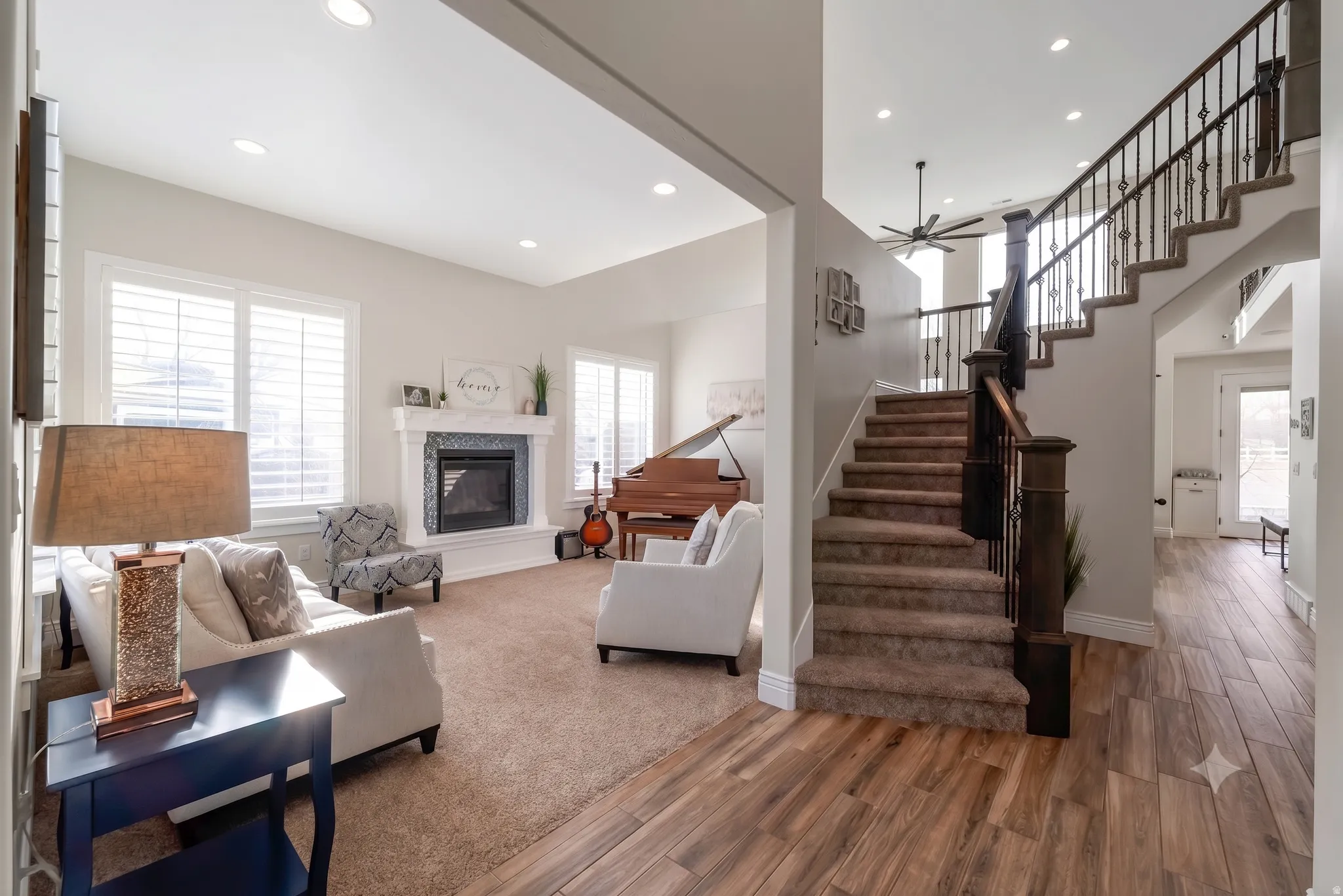 Living area featuring a fireplace with a tiled surround and white mantel, plantation shutters, and recessed lighting