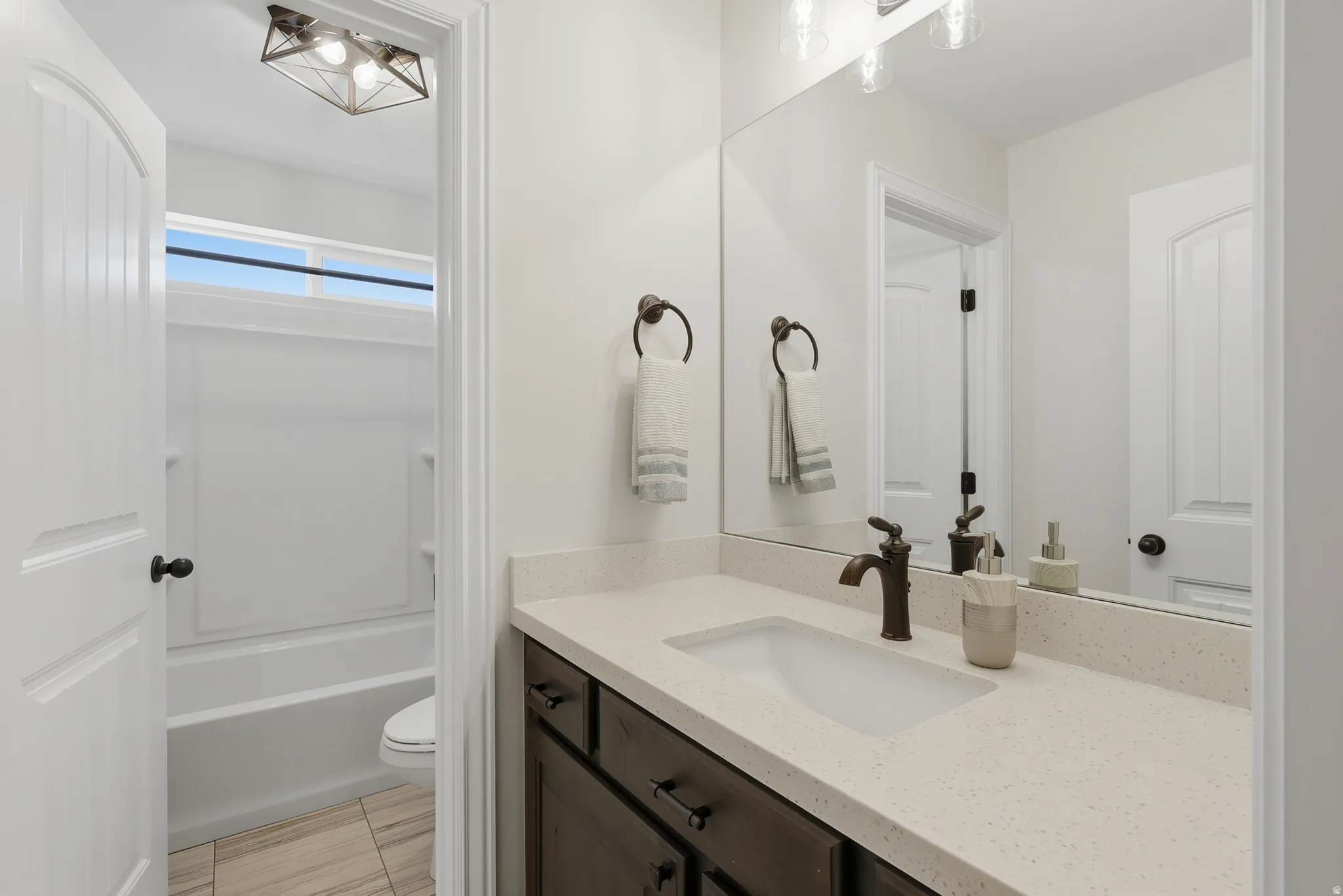White vanity with a single basin, light-toned countertop, and bronze-finish faucet