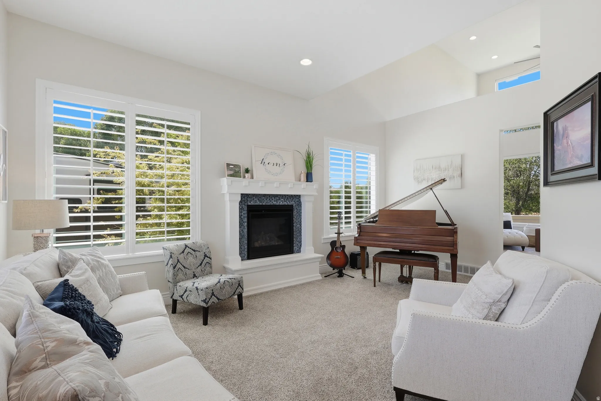 Living area featuring a fireplace with a tiled surround, high vaulted ceilings, and extensive window treatments
