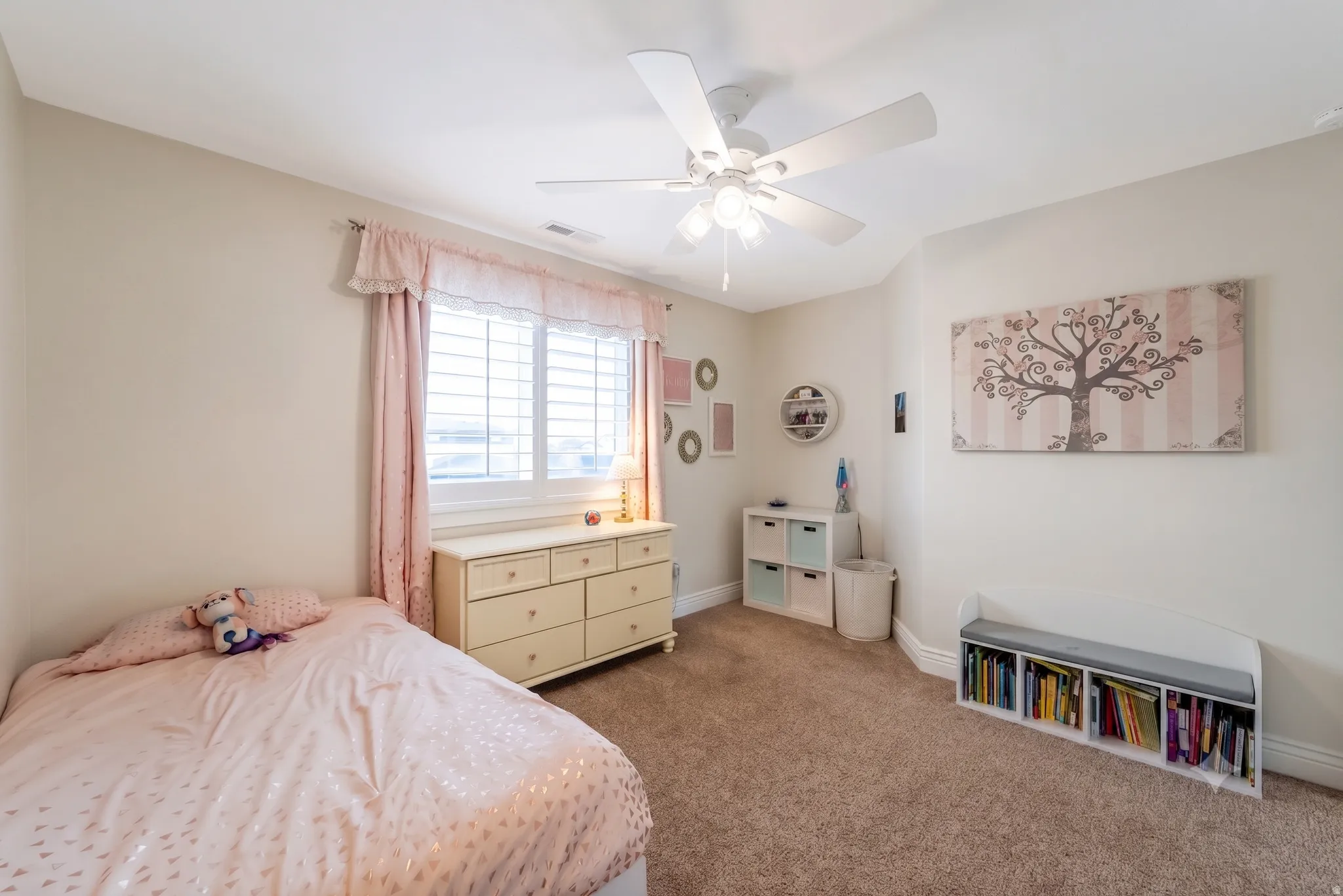 Carpeted room featuring a ceiling fan, window with plantation shutters, and light-colored walls