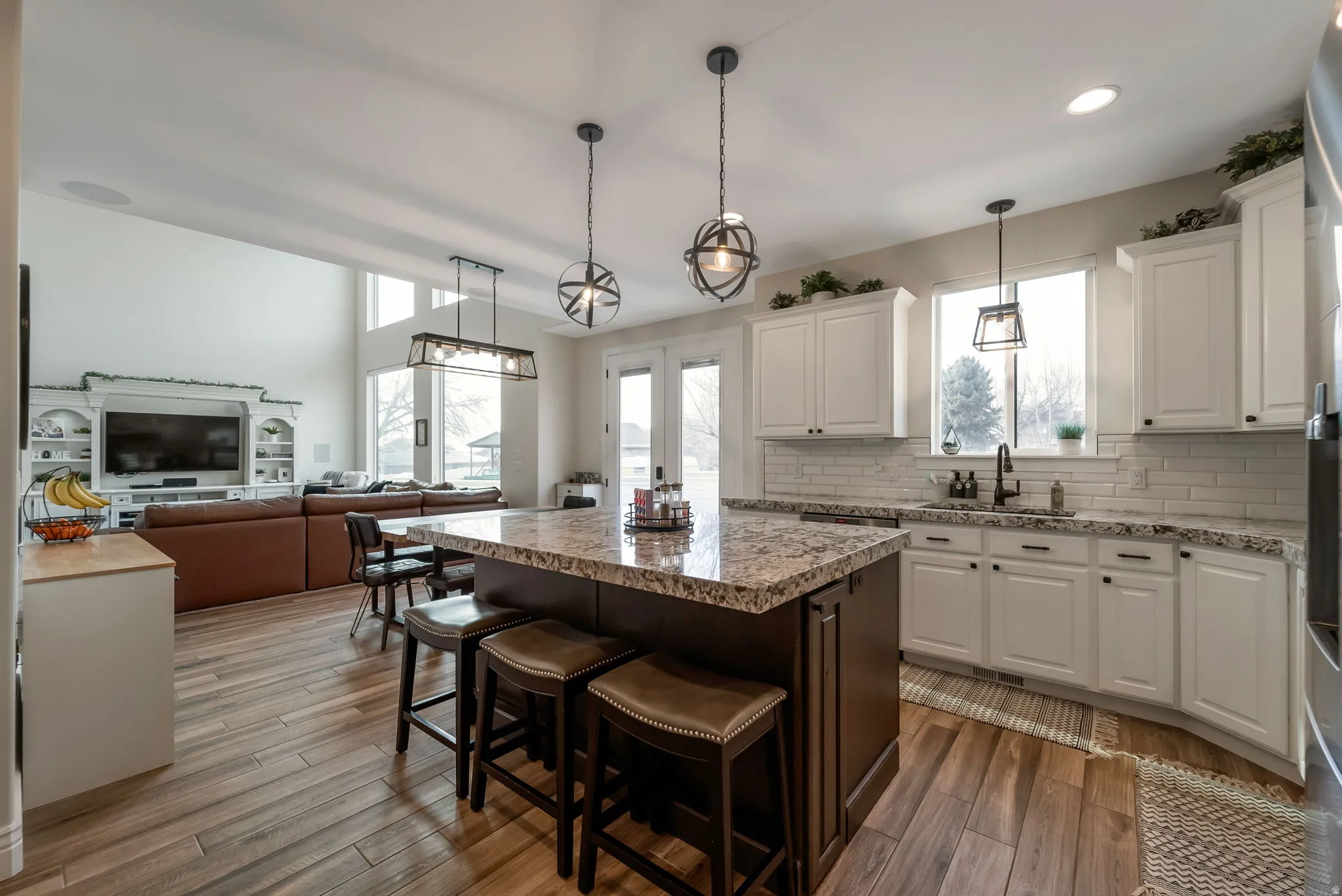 Kitchen featuring a large island with seating, white shaker cabinetry, white subway tile backsplash, and wood-finish flooring