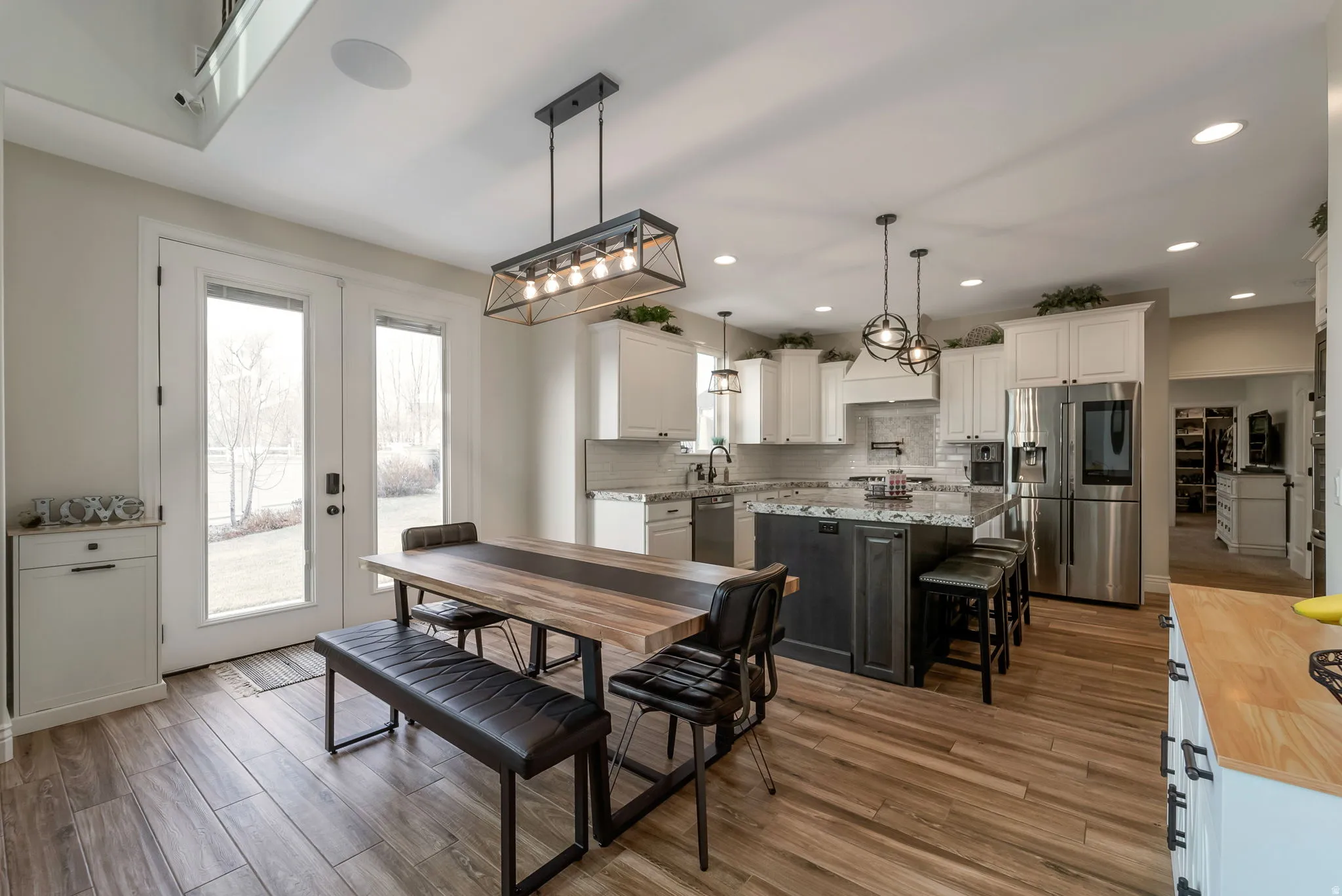 Gourmet kitchen featuring a center island with bar seating, stainless steel appliances, white cabinetry, and wood-finish flooring