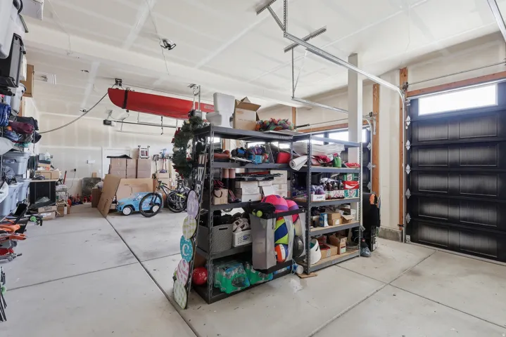 Attached garage space featuring a concrete floor, overhead storage system, and built-in shelving