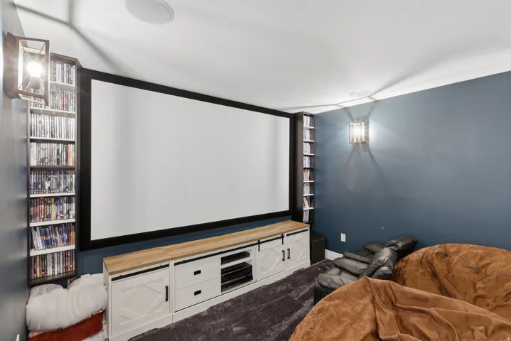 Built-in entertainment center with a large projection screen, integrated shelving units, and a wood-finish countertop