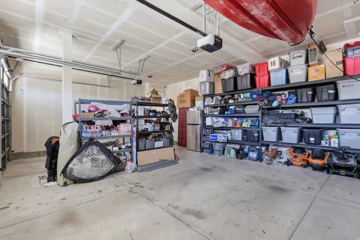 Garage with finished walls and ceiling, featuring overhead garage door tracks and permanent shelving units