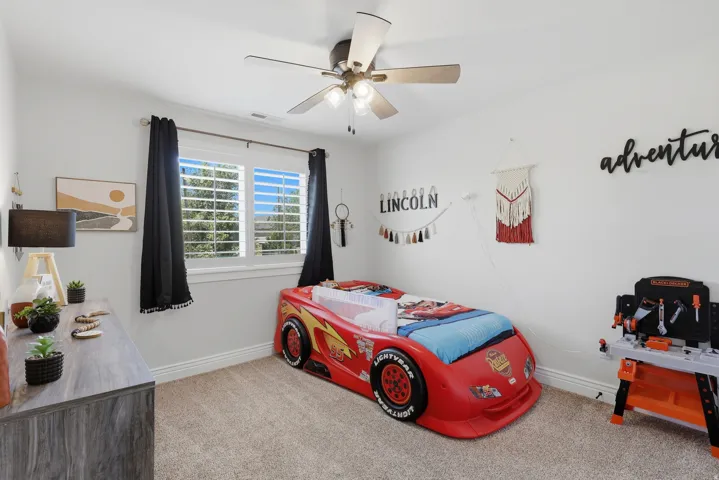 Recessed window with plantation shutters, ceiling fan with integrated lighting, and neutral-toned carpeting