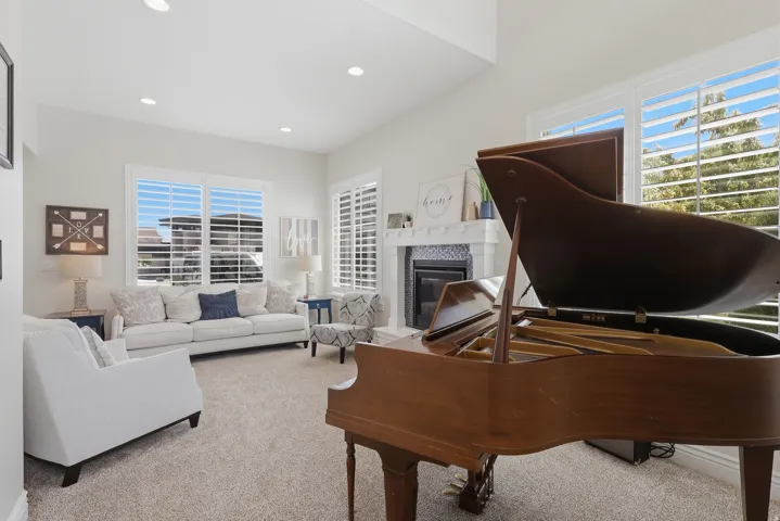 Living area featuring high vaulted ceilings, recessed lighting, multiple windows with shutters, and a fireplace with a decorative mantel and hearth