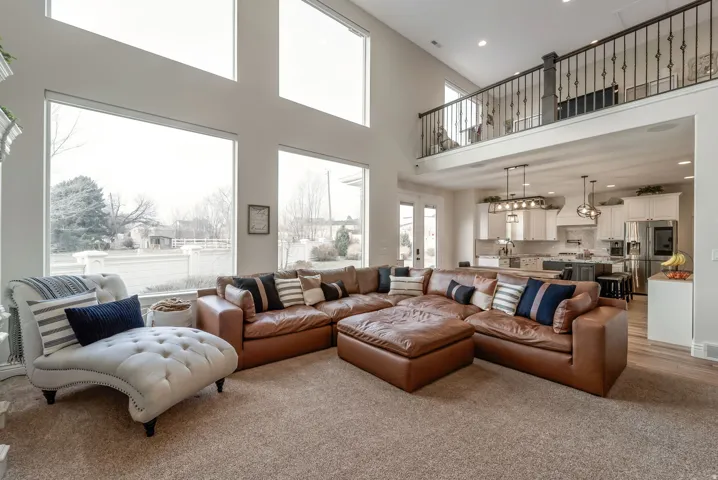High ceilings with upper transom windows, open concept kitchen, white shaker cabinetry, stainless steel appliances, and a wrought iron balcony overlooking the living space