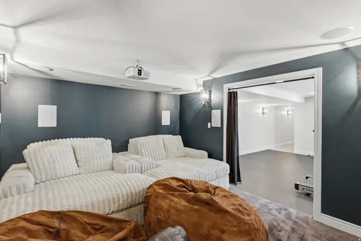 Integrated ceiling speakers, wall-mounted sconce lighting, recessed projector, and a wide cased opening