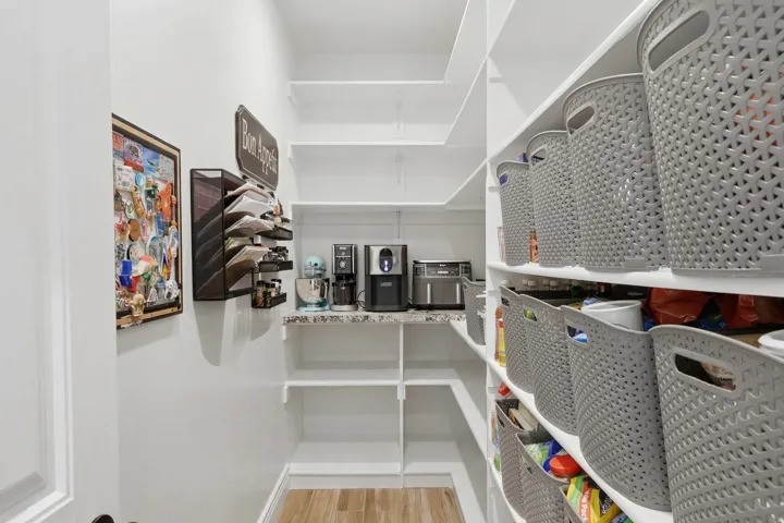 Spacious walk-in pantry with extensive built-in shelving, a countertop, and wood-finish flooring