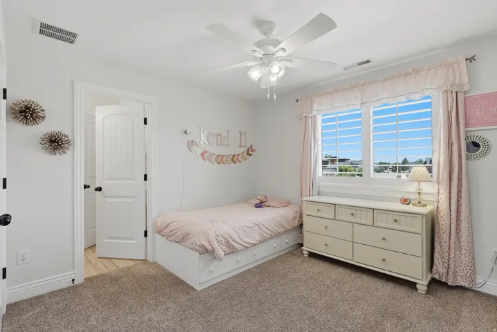 Carpeted room featuring a white ceiling fan with integrated lighting, a multi-pane window, and a paneled interior door