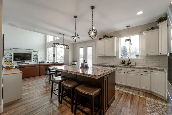 Kitchen featuring a large island with seating, white shaker cabinetry, white subway tile backsplash, and wood-finish flooring