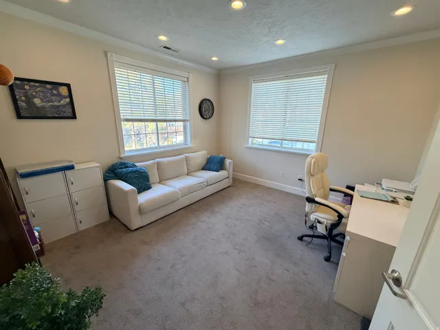Carpeted room featuring multiple windows with blinds, recessed lighting, and crown molding