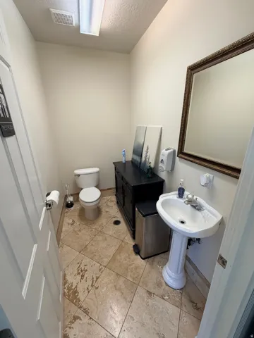 Pedestal sink with chrome faucet, framed mirror, and tile flooring