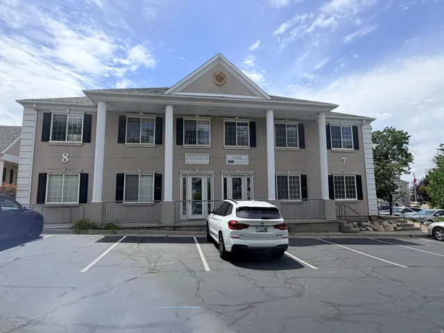 Two-story commercial building with a stucco exterior and prominent white columns