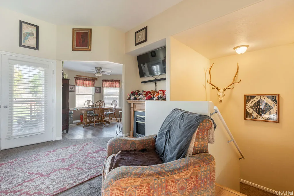 Archway entry, built-in fireplace, ceiling fan, white door with window pane, wood-finish flooring