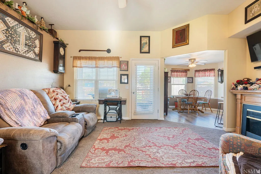 Carpeted living area with a built-in fireplace, a white exterior door, and an arched opening to an adjoining room with wood-finish flooring