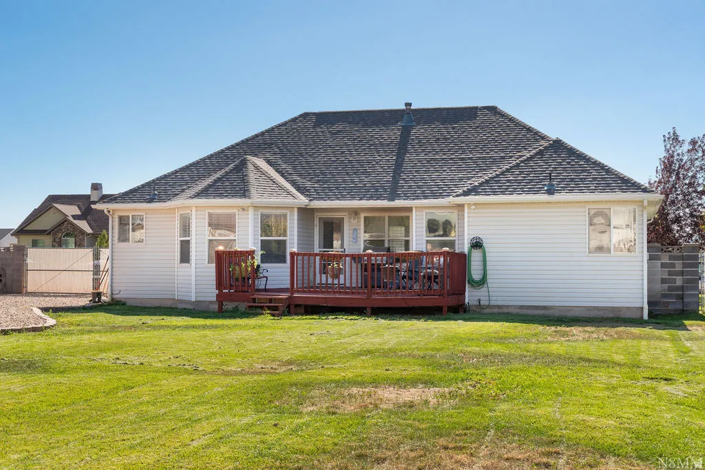Charming single-story residence featuring a spacious covered front porch with wood railings, fresh white vinyl siding, and a multi-pitched asphalt shingle roof