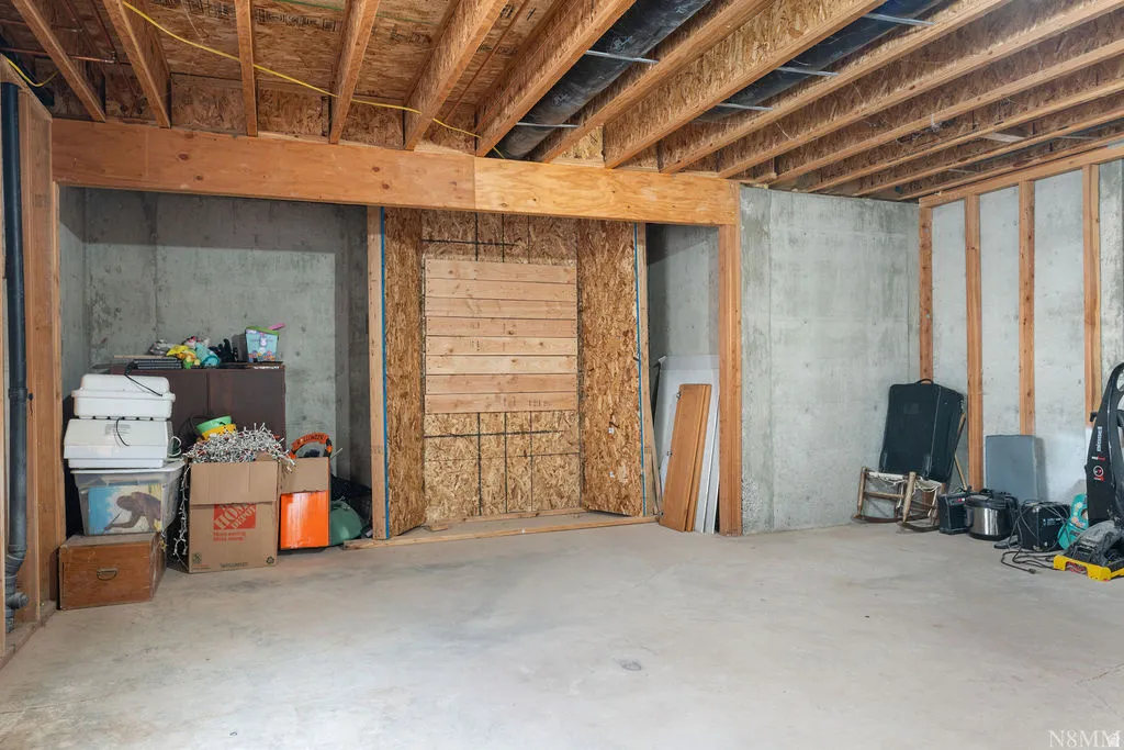 Unfinished basement with concrete flooring, exposed wooden joists, and concrete foundation walls