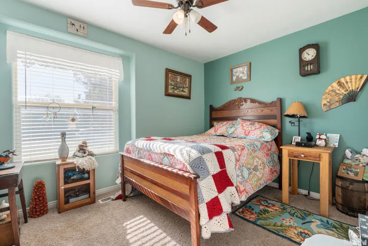 Carpeted room featuring a ceiling fan with light fixture, a window with blinds, and painted walls