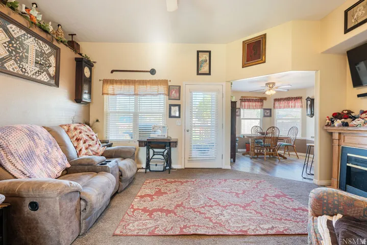 Carpeted living area with a built-in fireplace, a white exterior door, and an arched opening to an adjoining room with wood-finish flooring