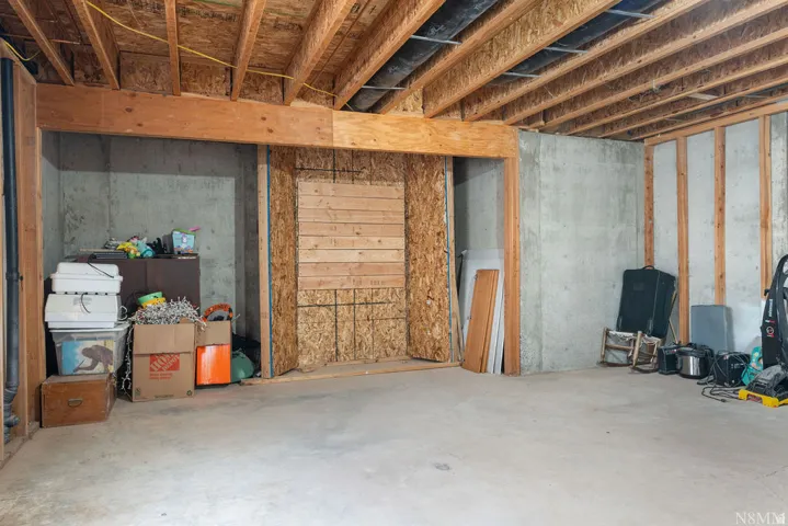 Unfinished basement with concrete flooring, exposed wooden joists, and concrete foundation walls