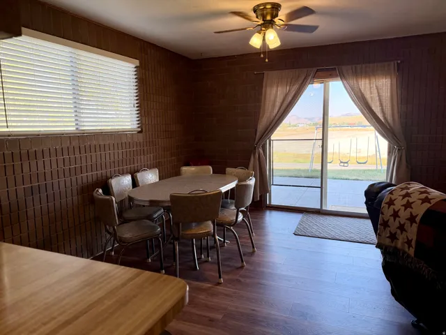 Spacious dining area with wood-finish flooring, round dining table with seating for four, and glass sliding doors opening to waterfront scenery