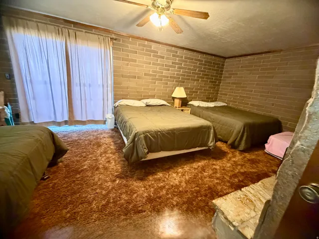 Brick-finish wall, ceiling fan with integrated lighting, built-in stone shelf, and wood trim accents