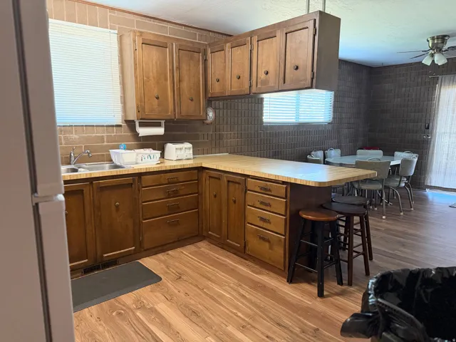 Spacious kitchen featuring warm wood cabinetry with ample storage, light countertops, stainless steel appliances, and a convenient island with seating