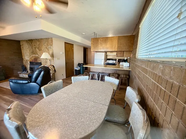 Open-concept living and dining area featuring wood-finish flooring, brick accent walls, and recessed ceiling lighting
