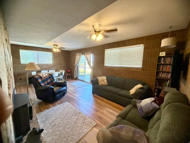 Wood-finish flooring throughout, brick-patterned wall covering, and multiple ceiling fans