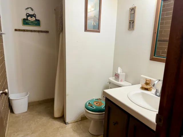 Bathroom featuring a ceramic sink with wood-finish vanity cabinetry, tile flooring, and a shower enclosure with curtain rod