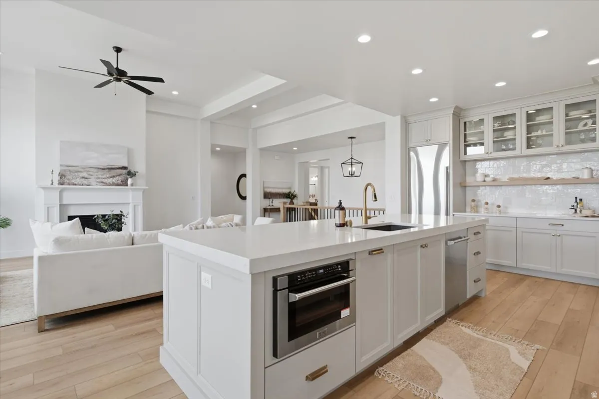 Spacious kitchen island with a built-in microwave, paneled cabinetry, and a single-basin sink with a gooseneck faucet