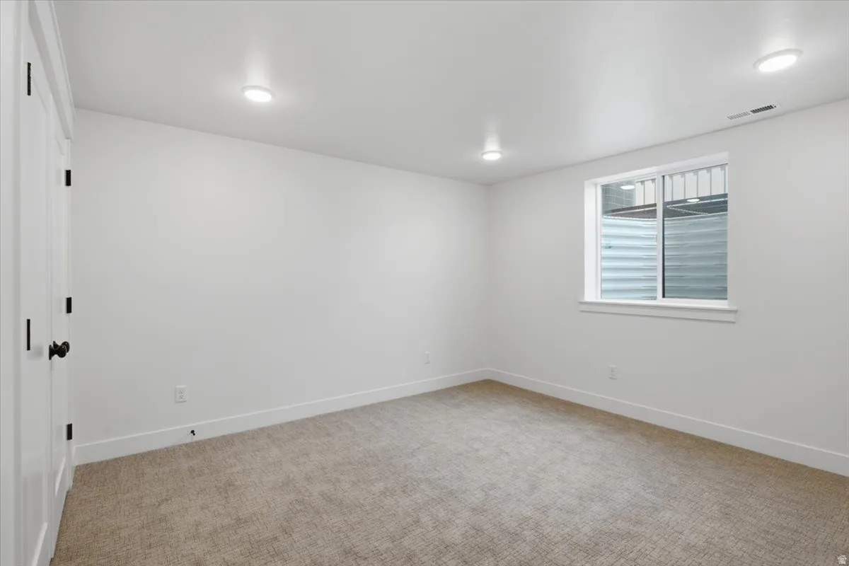 Light-toned wall-to-wall carpeting, white walls, recessed ceiling lighting, and a white-framed window
