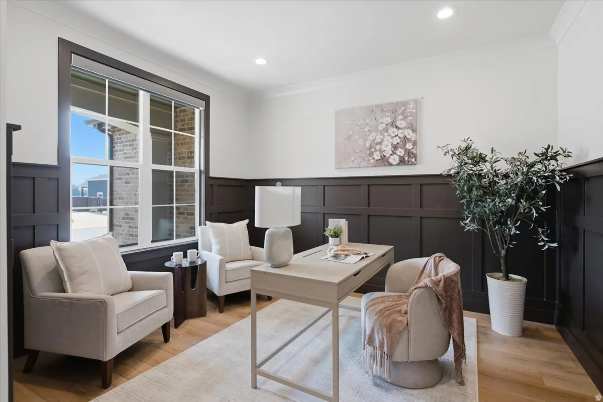 Wood-finish flooring with a decorative area rug, dark wainscoting, recessed lighting, and a large window with gridded panes