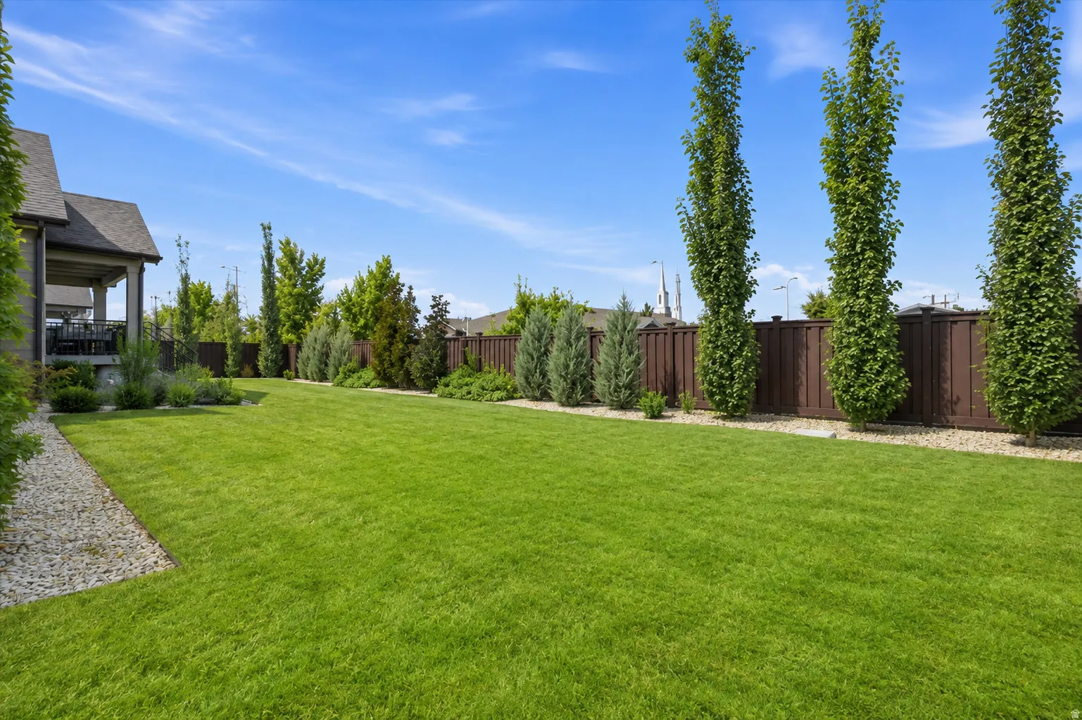 Expansive lawn area, mature trees, and a privacy fence