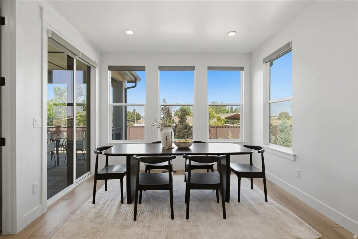 Wood-finish flooring, recessed lighting, and multiple windows with roller shades