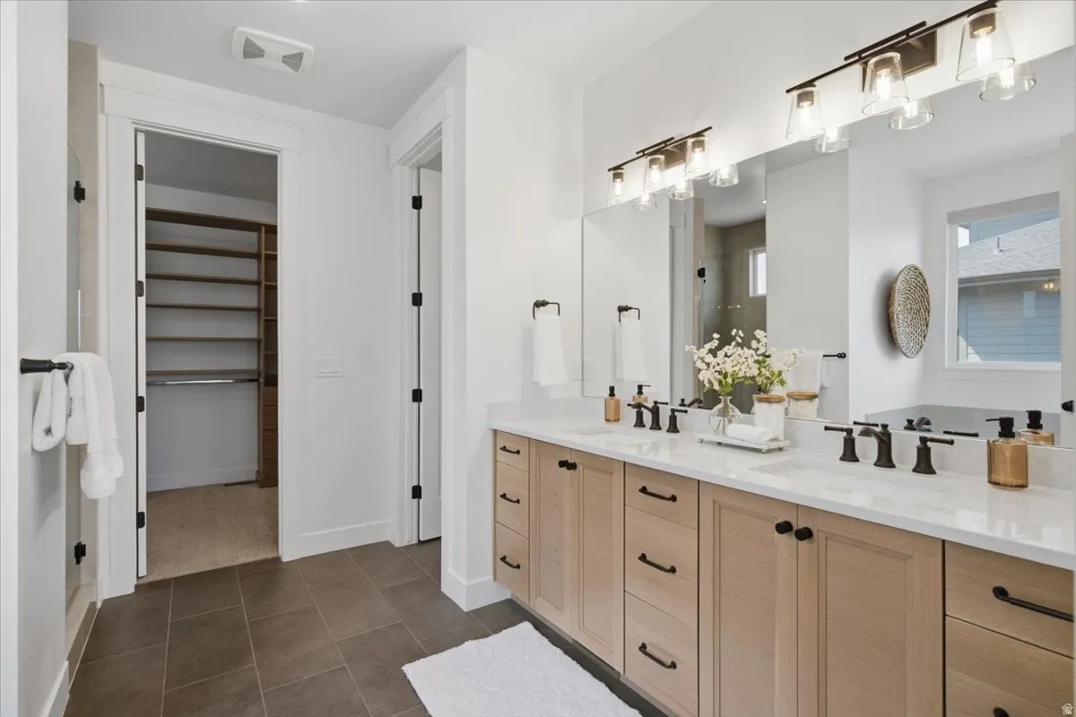 Dual vanity with light wood-finish cabinetry, white countertops, and matte black fixtures